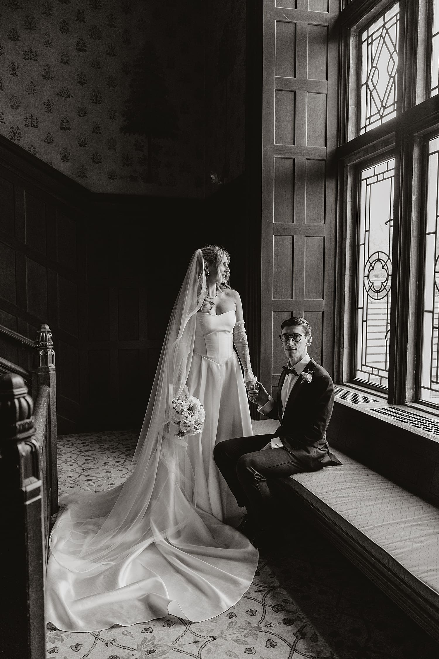 newlyweds sit in big historic window by Kelly Jean Photography