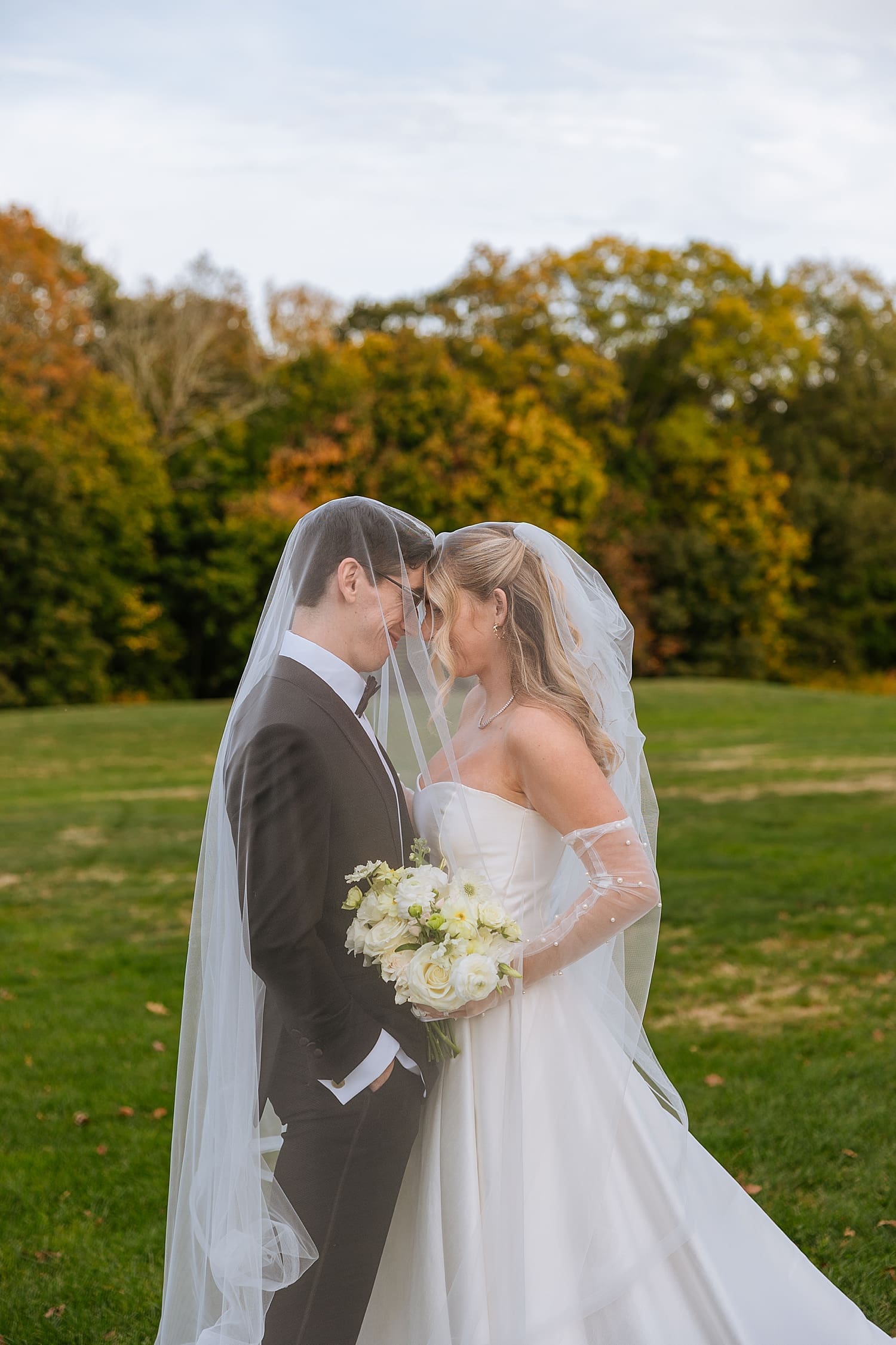 newlyweds under a veil on the lawn by Kelly Jean Photography