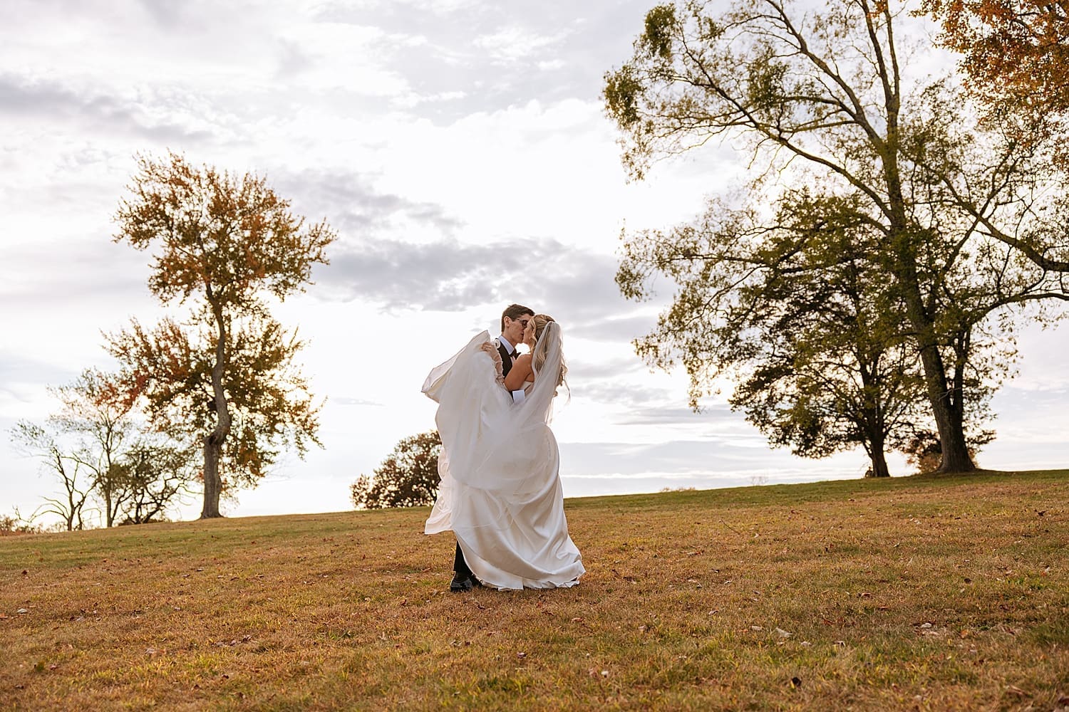 newlyweds dance on hill at Waveny House during golden hour