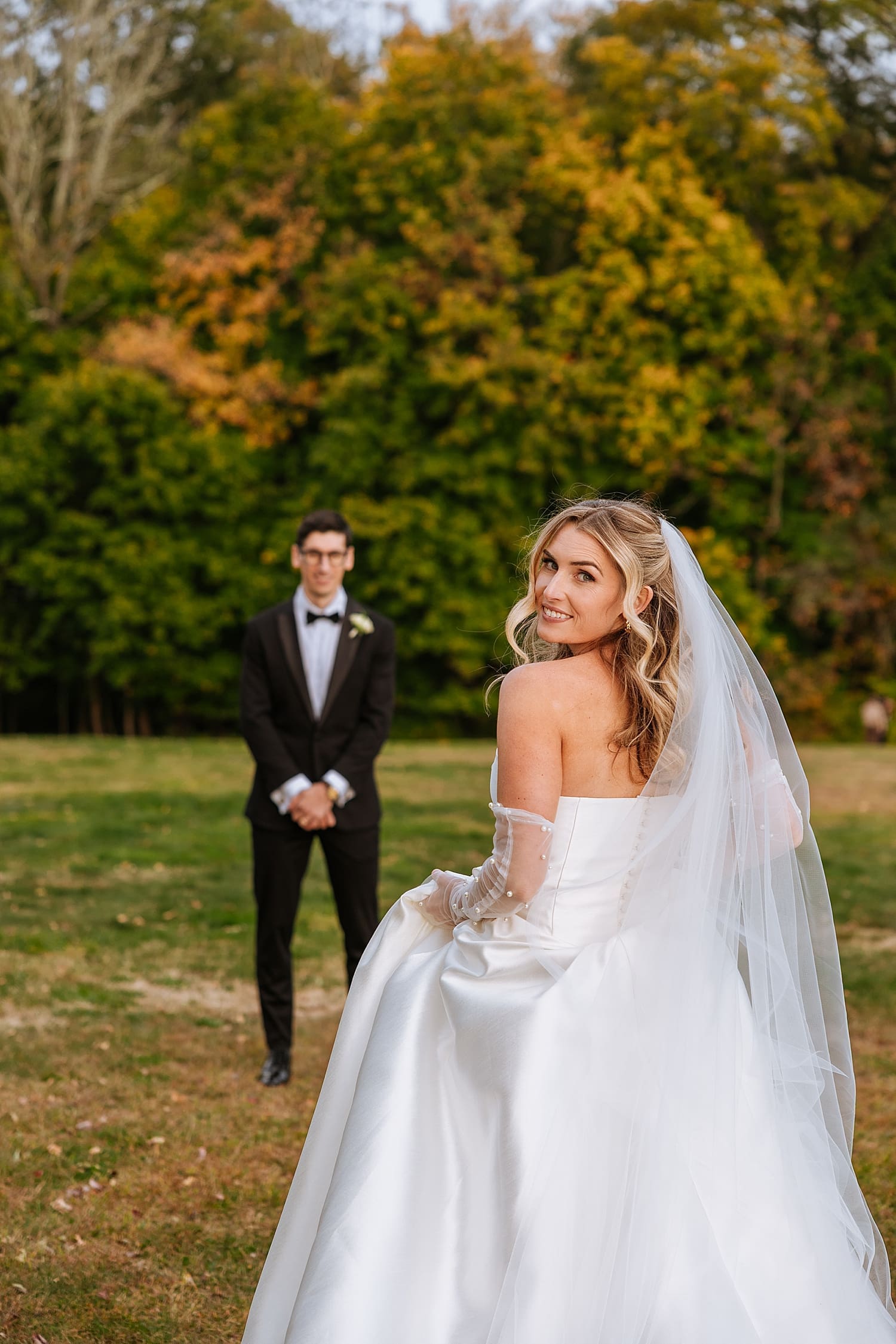 bride looks over her shoulder while walking to her groom by East Coast wedding photographer