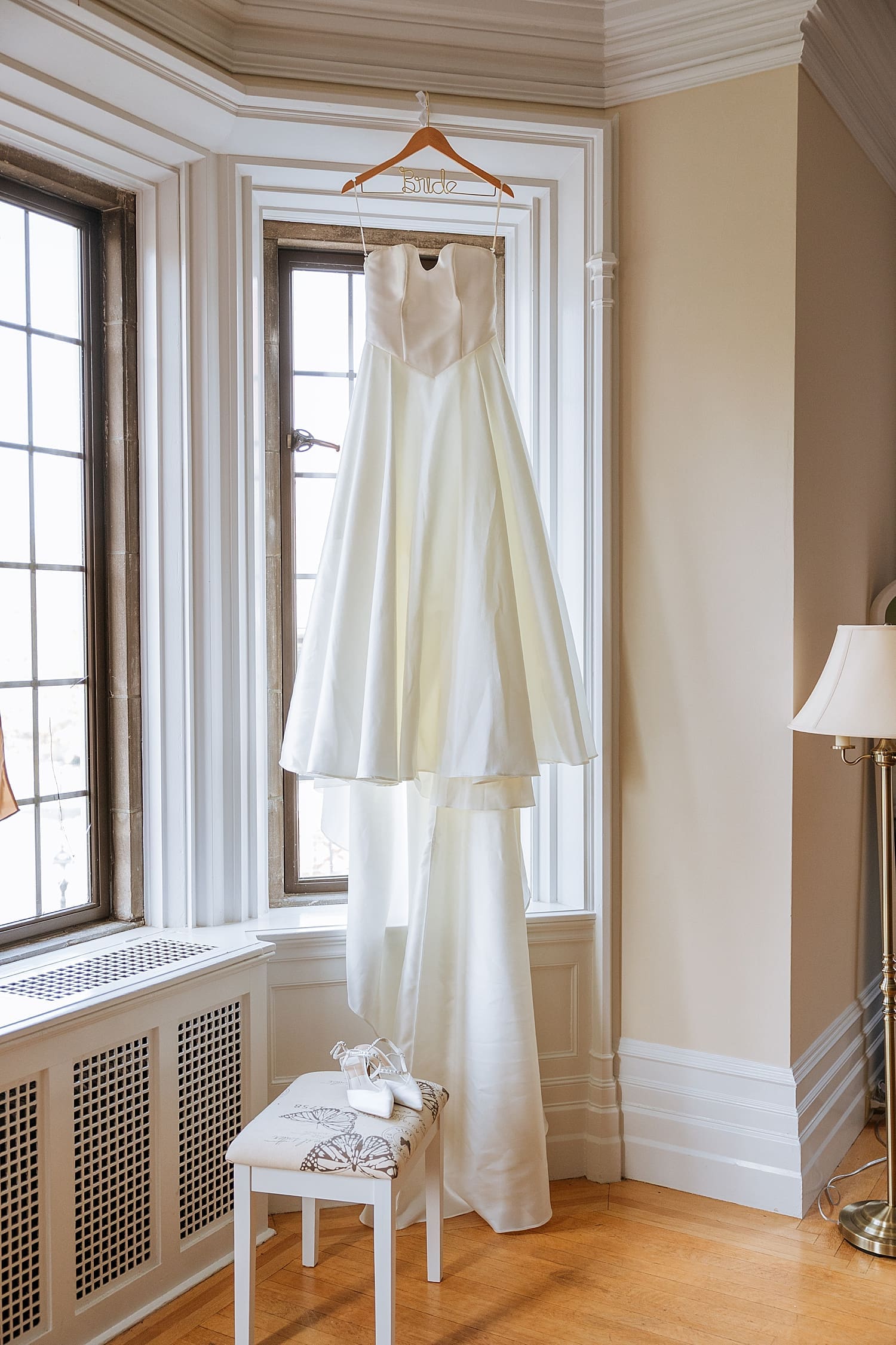 wedding gown hangs in the window of historic house by Kelly Jean Photography