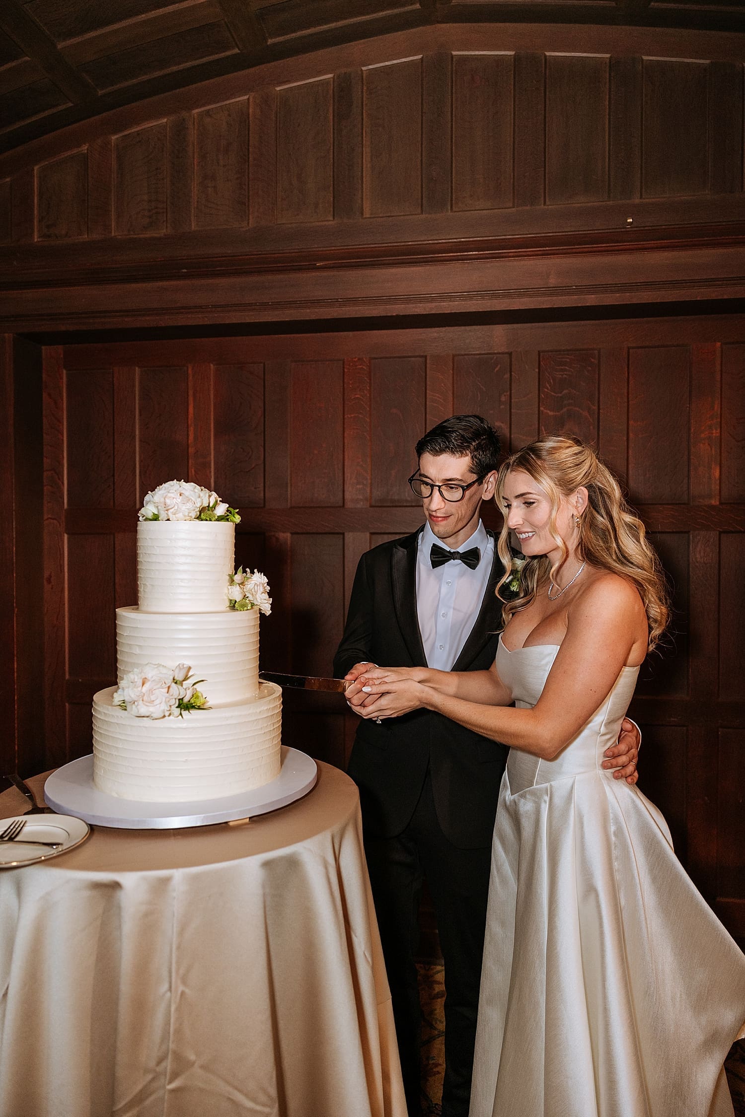 newlyweds cut three tier white cake by Kelly Jean Photography