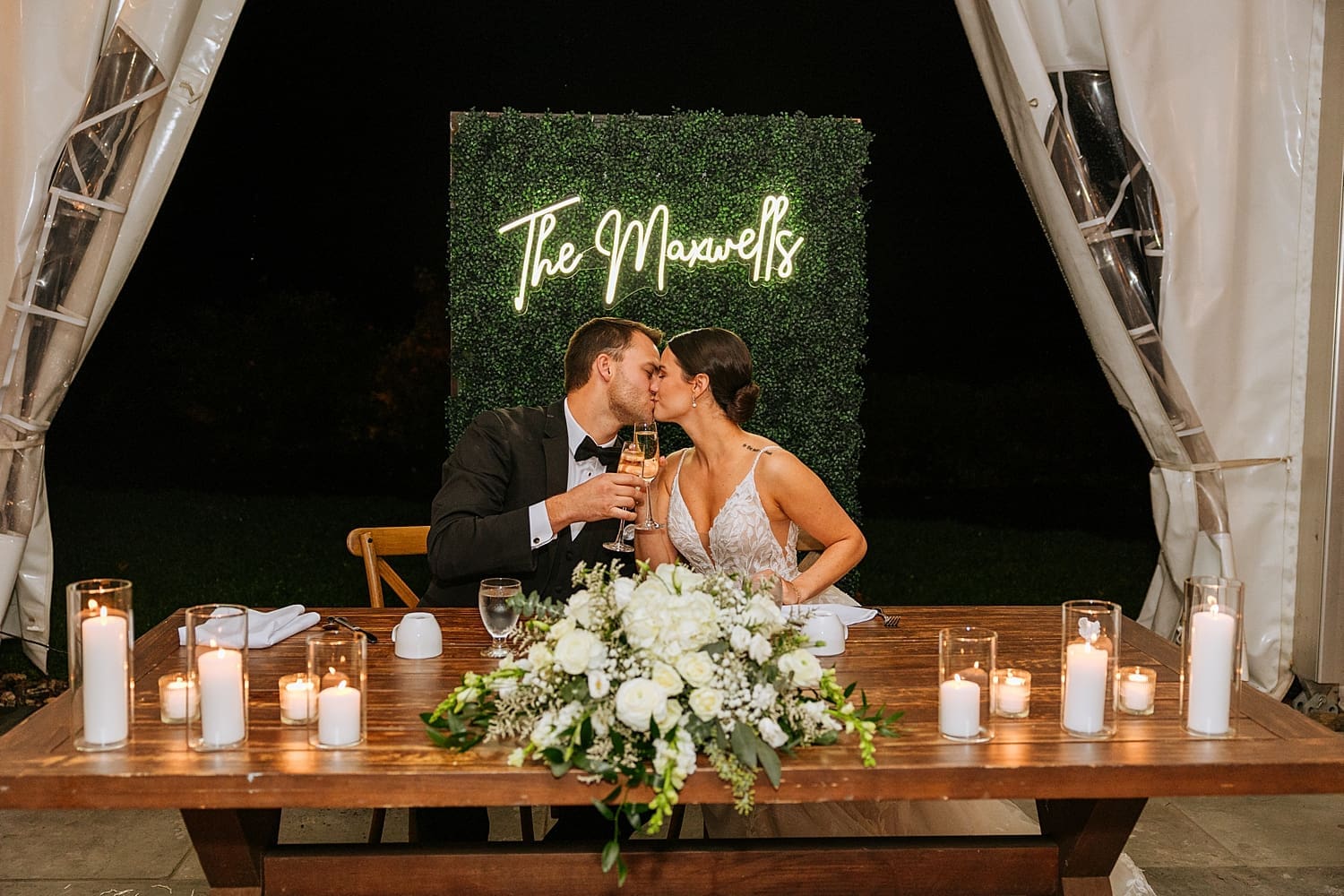 husband and wife share a kiss at reception table by Kelly Jean Photography