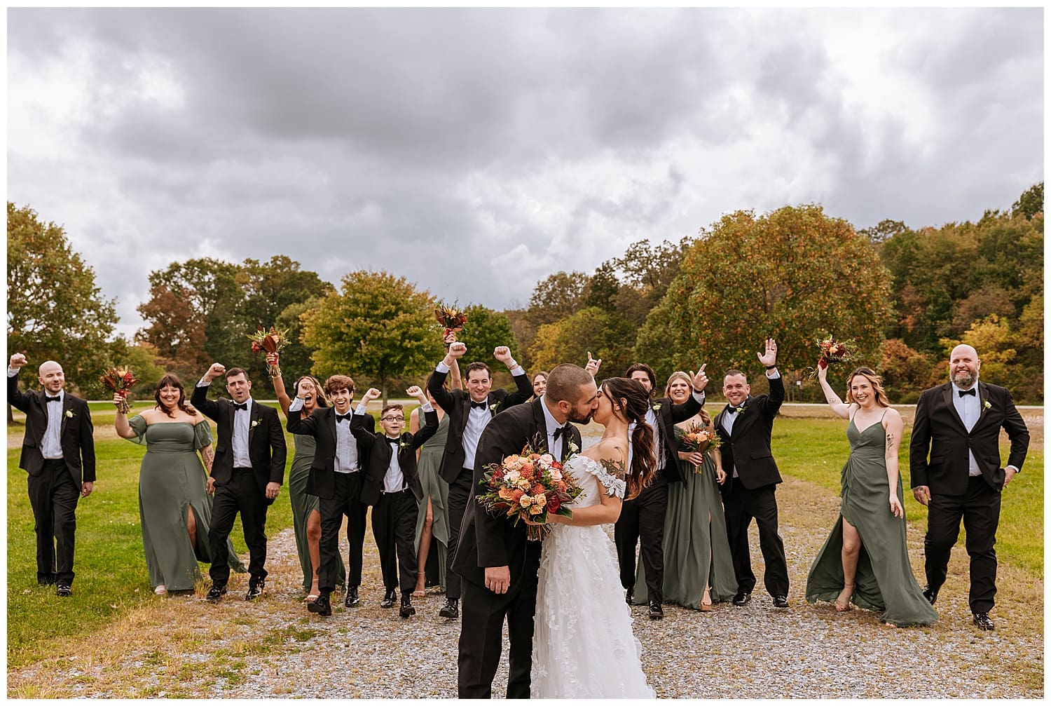 bride and groom kiss in front of cheering wedding party by Hudson Valley photographer