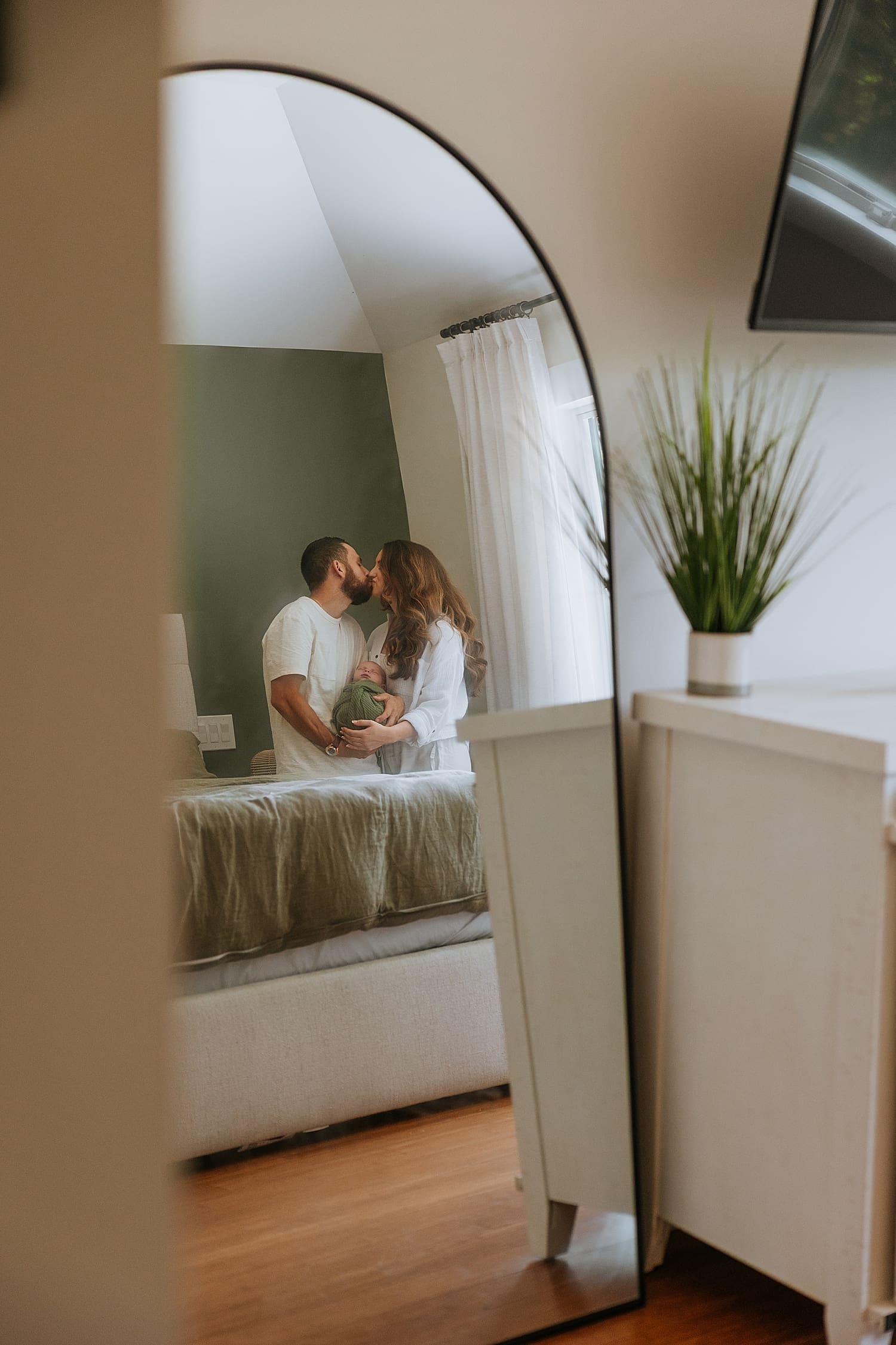new parents share a kiss while holding baby by Kelly Jean Photography